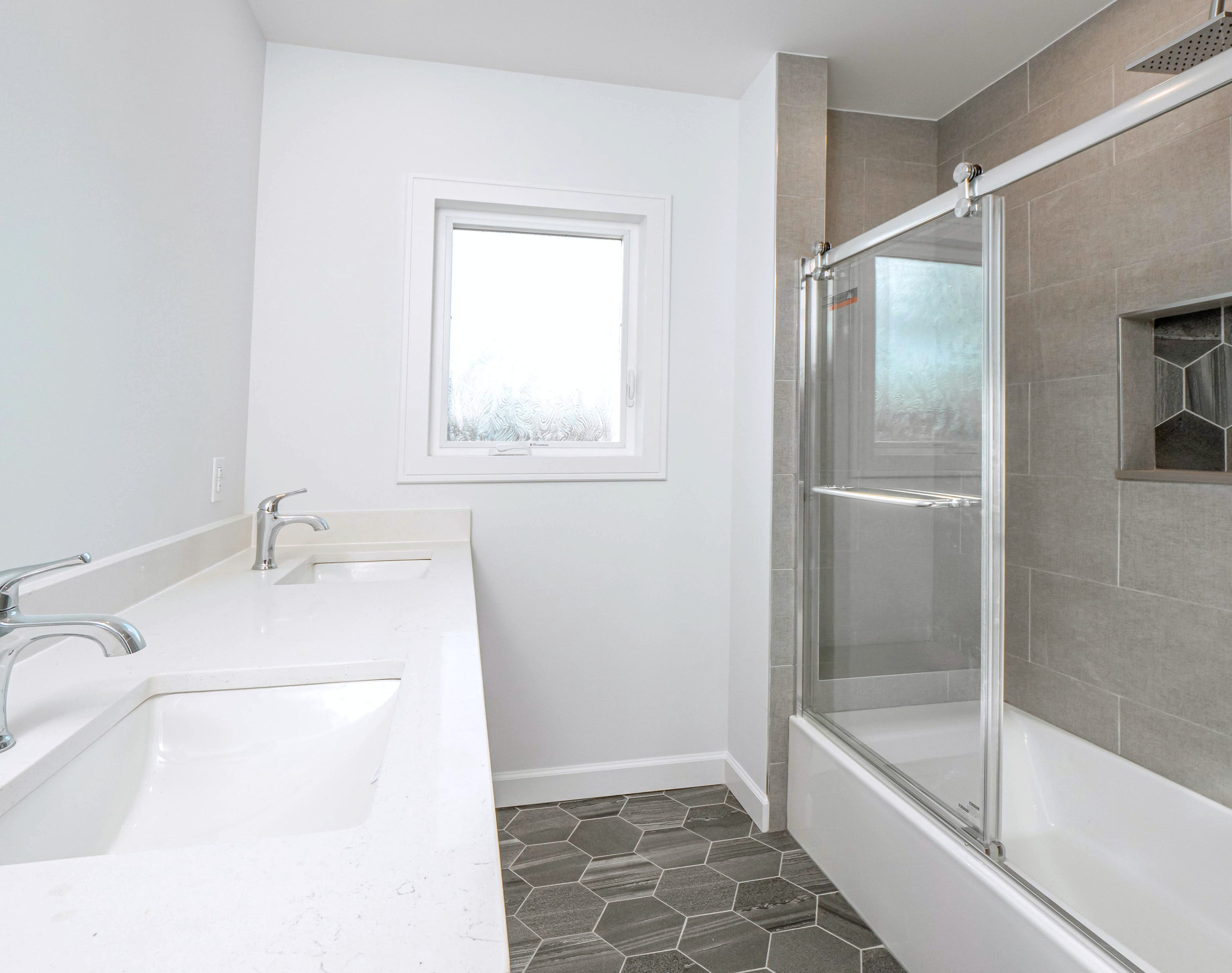 Bathroom with double vanity, tiled tub shower with sliding glass door